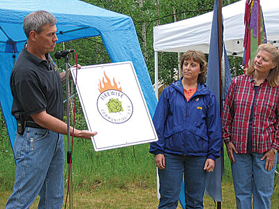 Ken Bullman, Mat Su Area Forester, presents community with Firewise Communites/USA signage.