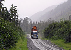 A large truck in Southeast Alaska driving down a road while loaded with logs.